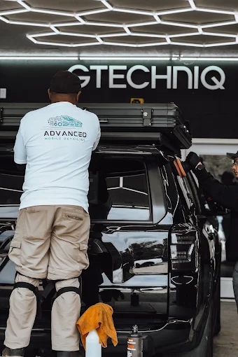 Technician detailing a black SUV