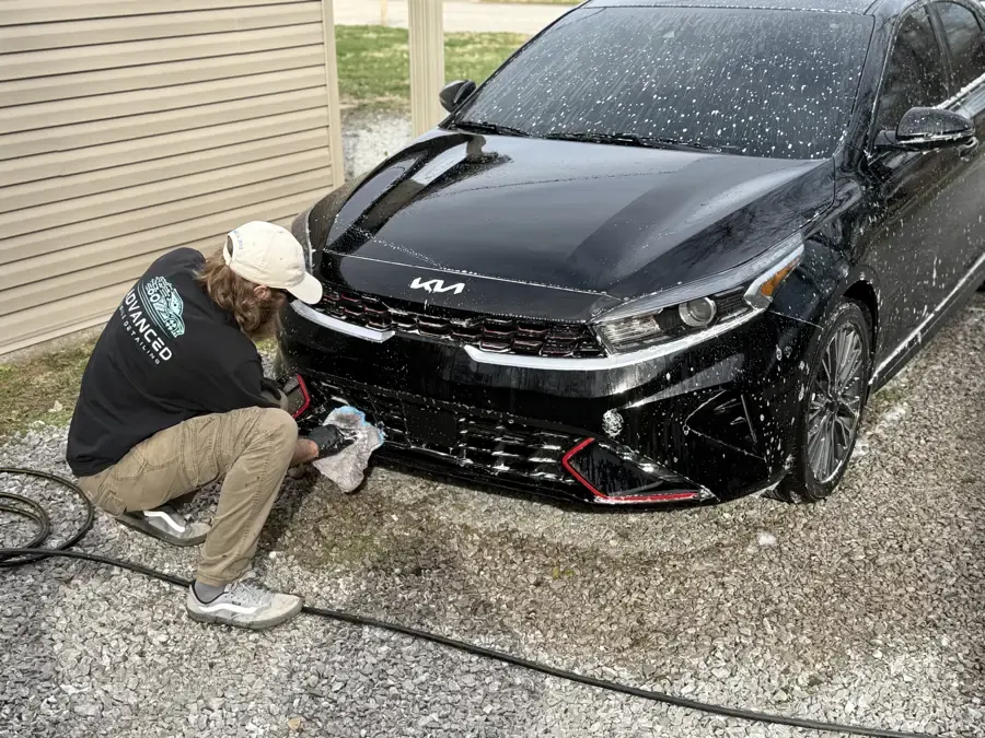 AMD tech cleaning wheels during a driveway exterior detail in Louisville, KY